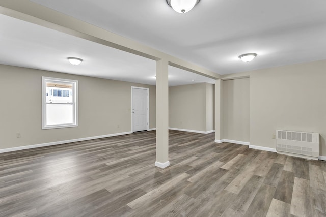 basement with radiator, baseboards, and wood finished floors