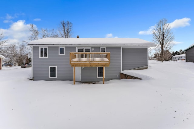 snow covered rear of property with a deck