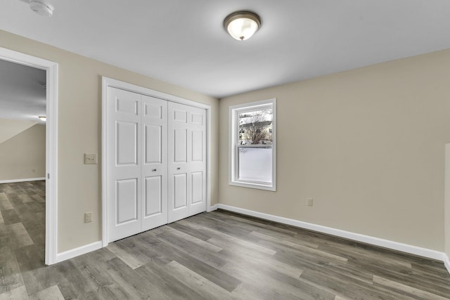 unfurnished bedroom with a closet, baseboards, and wood finished floors