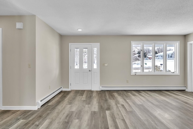 entrance foyer with a baseboard heating unit, a textured ceiling, wood finished floors, and baseboards