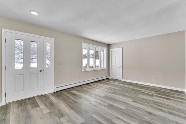 entryway with plenty of natural light, a textured ceiling, a baseboard radiator, and wood finished floors