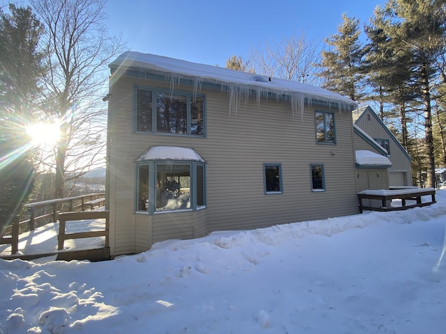 snow covered back of property featuring a garage