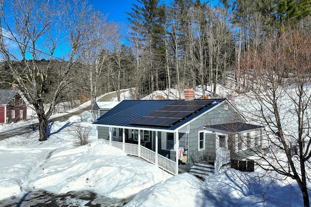 view of front of property featuring covered porch and roof mounted solar panels