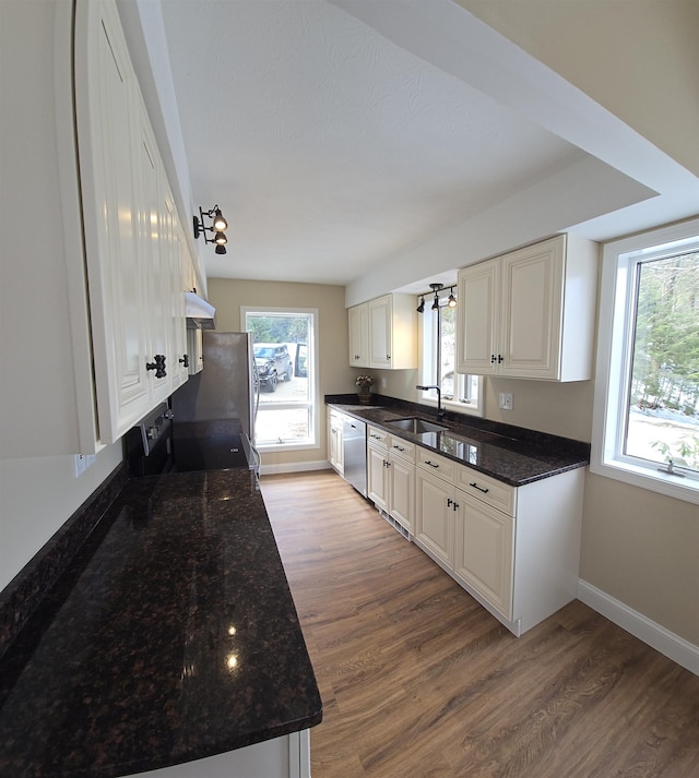 kitchen featuring appliances with stainless steel finishes, a sink, baseboards, and wood finished floors