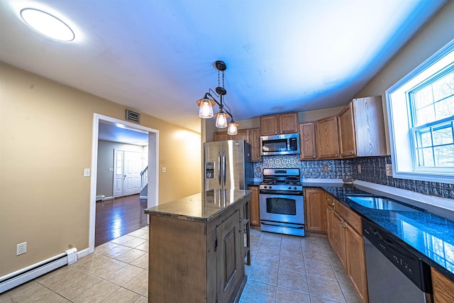 kitchen with a baseboard heating unit, appliances with stainless steel finishes, decorative backsplash, and light tile patterned flooring