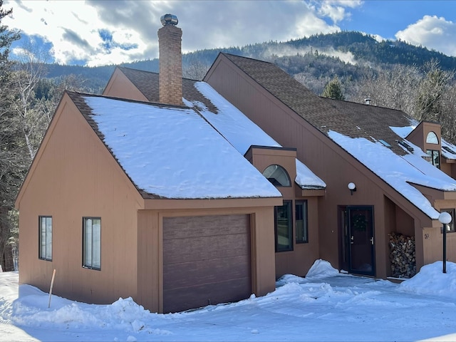 exterior space featuring a shingled roof, a chimney, and an attached garage