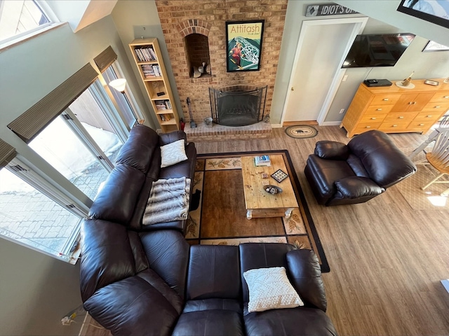 living area with a brick fireplace, baseboards, and wood finished floors