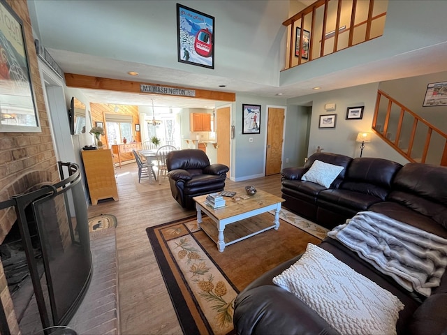 living area featuring stairway, a brick fireplace, wood finished floors, and a towering ceiling