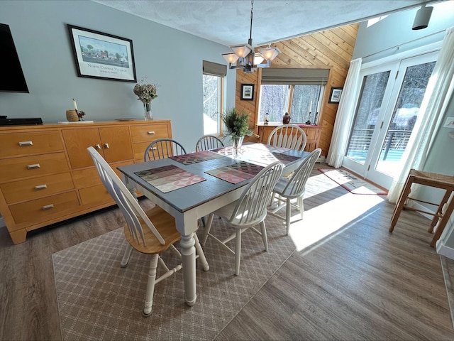 dining room featuring a notable chandelier, wooden walls, and wood finished floors