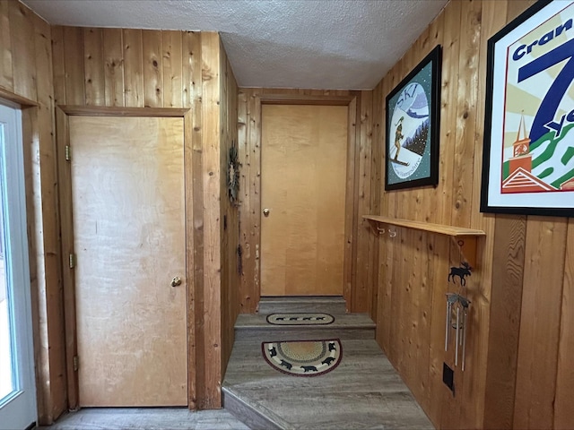 entryway with a textured ceiling and wood walls