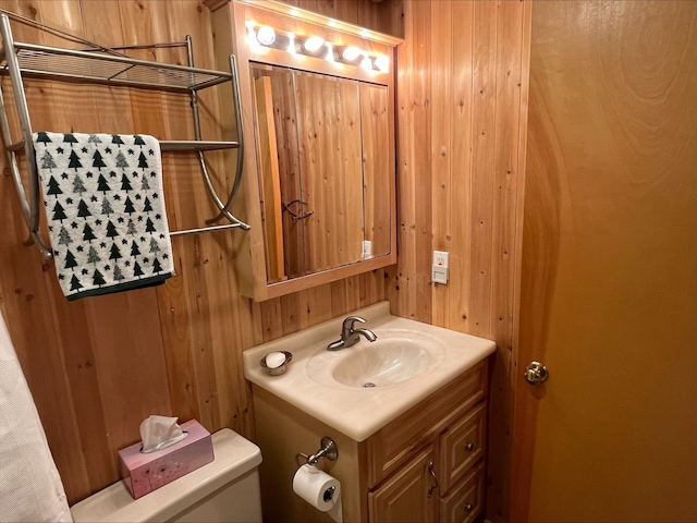 half bath featuring toilet, wood walls, and vanity