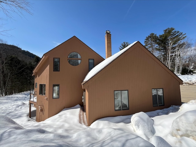 snow covered house featuring a chimney