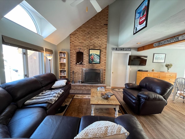 living area featuring ceiling fan, a fireplace, high vaulted ceiling, and wood finished floors