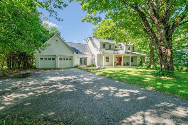 view of front of house featuring a garage, driveway, metal roof, a standing seam roof, and a front lawn