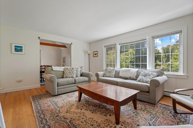 living area featuring a baseboard heating unit, baseboards, and light wood finished floors