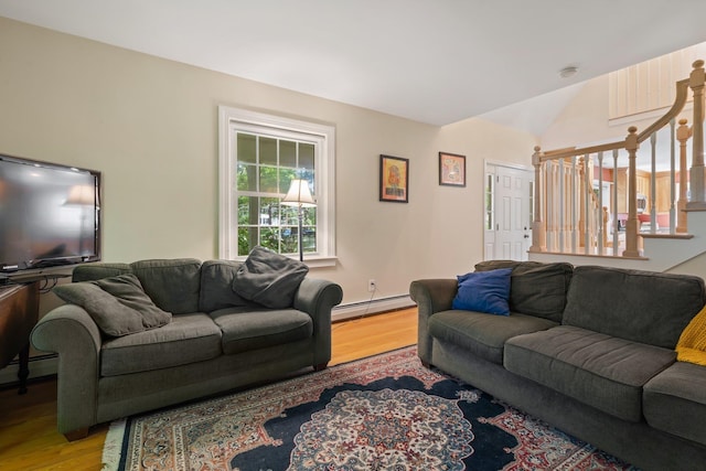 living room featuring vaulted ceiling, stairway, baseboard heating, and light wood-type flooring