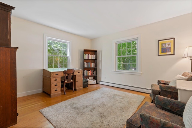 office featuring a baseboard radiator, a healthy amount of sunlight, light wood-style flooring, and baseboards