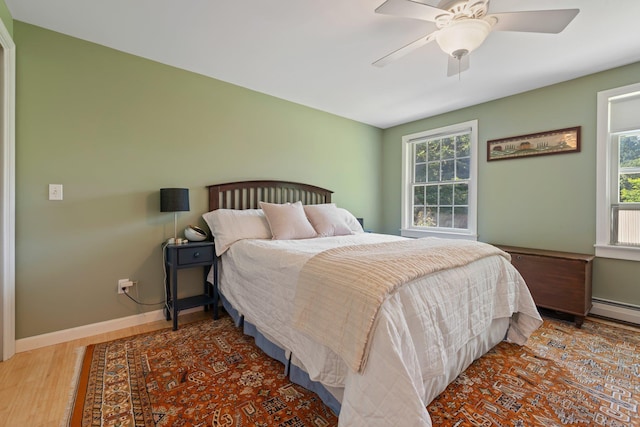 bedroom with a ceiling fan, multiple windows, baseboards, and wood finished floors