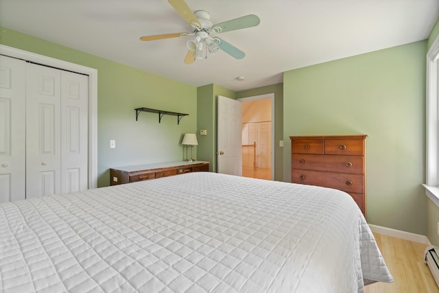 bedroom with baseboards, a ceiling fan, light wood-type flooring, a baseboard heating unit, and a closet