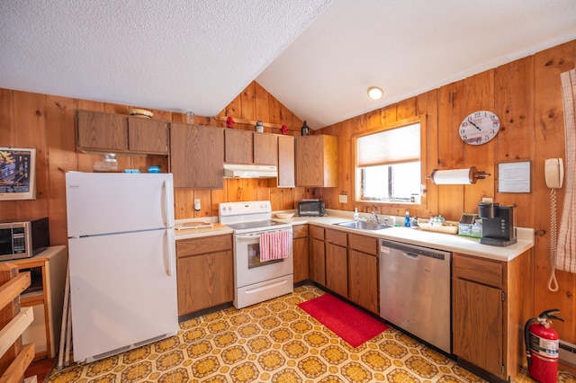 kitchen featuring under cabinet range hood, wooden walls, stainless steel appliances, and light countertops