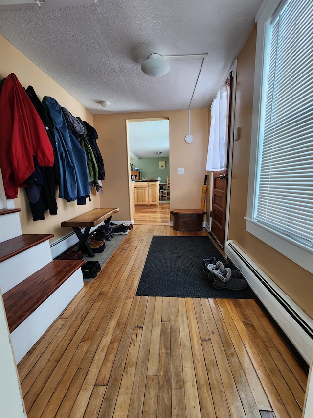 mudroom featuring wood-type flooring, baseboards, baseboard heating, and a textured ceiling