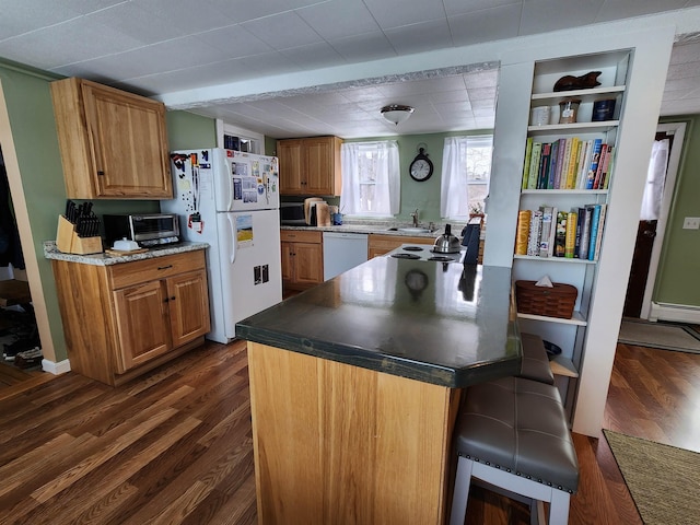 kitchen with dark wood-type flooring, a breakfast bar, white appliances, and a toaster