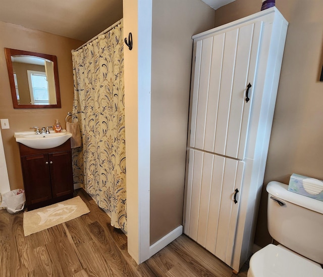 full bathroom featuring toilet, baseboards, wood finished floors, and vanity