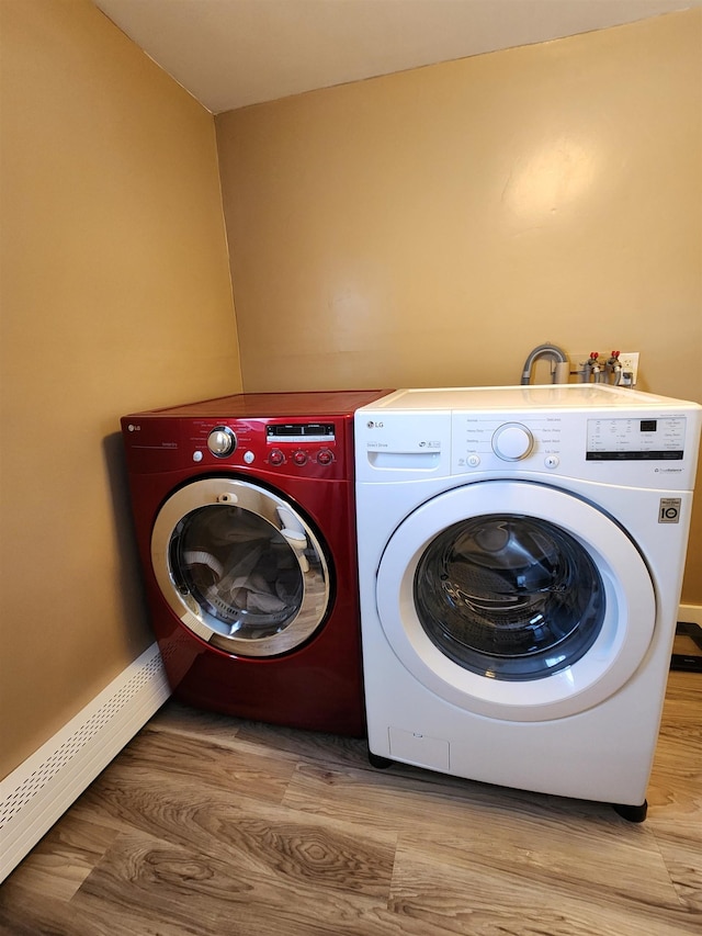 washroom featuring laundry area, a baseboard heating unit, separate washer and dryer, and wood finished floors