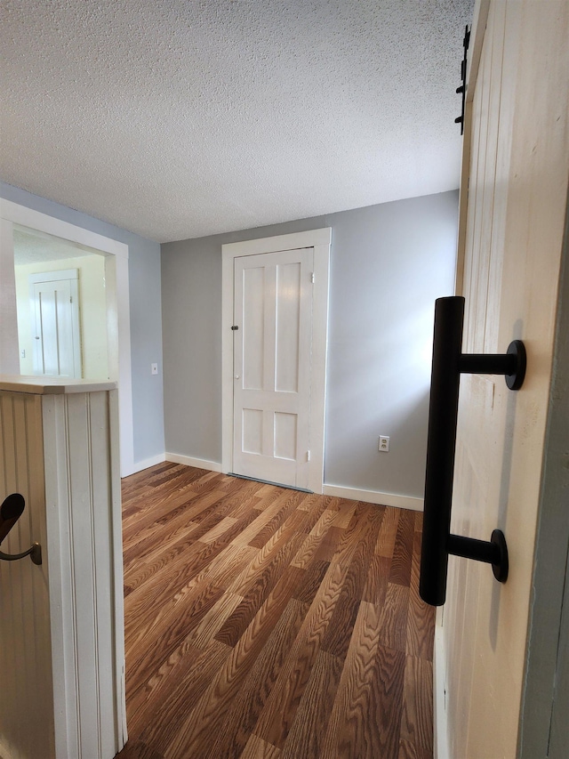 spare room with a textured ceiling, wood finished floors, and baseboards