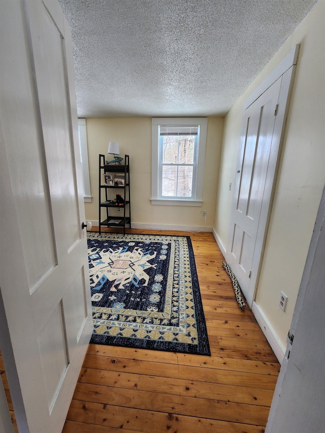 doorway with a textured ceiling, baseboards, and light wood-style floors