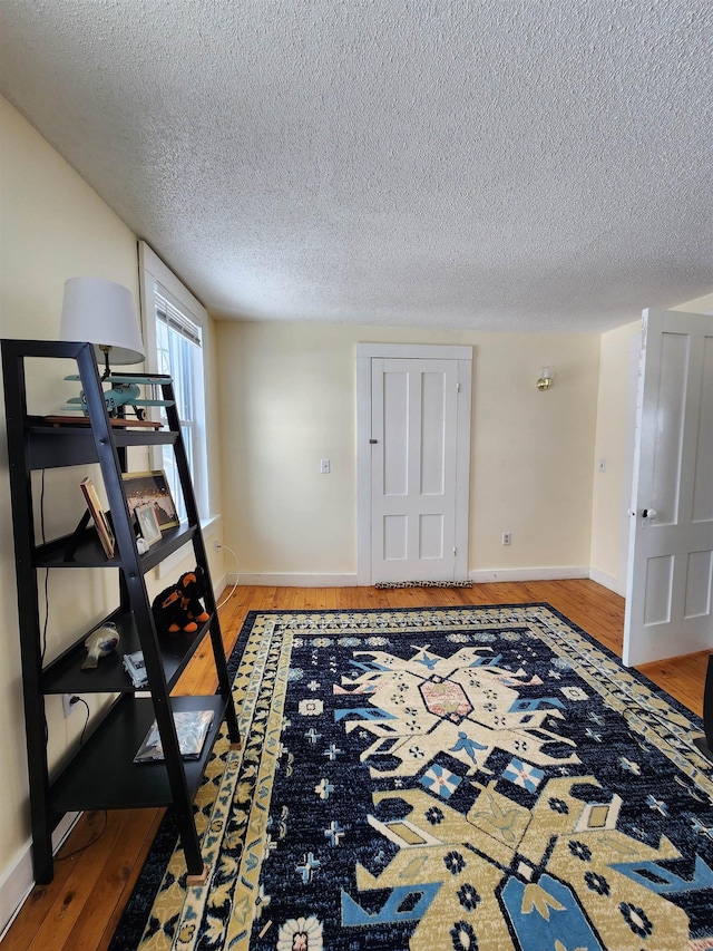 interior space featuring light wood-style floors, a textured ceiling, and baseboards