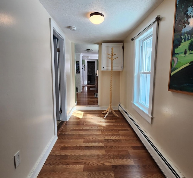 corridor with a textured ceiling, a baseboard radiator, dark wood finished floors, and baseboards