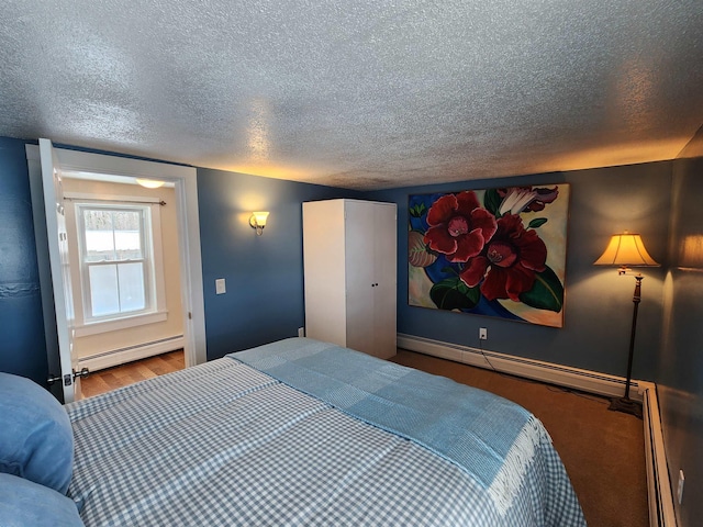 bedroom with baseboards, a textured ceiling, baseboard heating, and wood finished floors