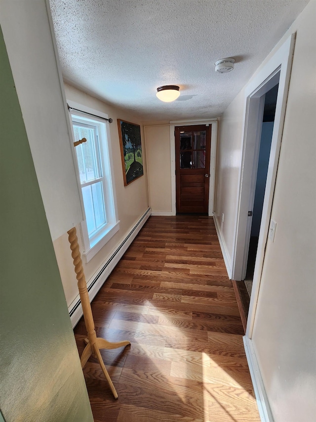 corridor featuring baseboards, a textured ceiling, a baseboard heating unit, and wood finished floors