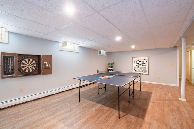 rec room featuring a baseboard heating unit, a paneled ceiling, baseboards, and light wood finished floors