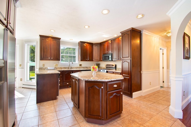 kitchen featuring arched walkways, a baseboard heating unit, stainless steel appliances, a kitchen island, and ornamental molding