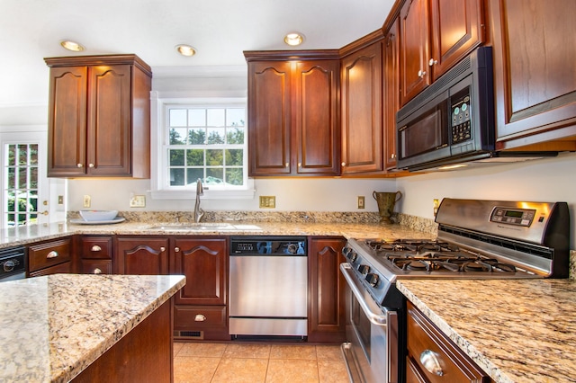 kitchen featuring stainless steel appliances, light tile patterned flooring, a sink, and light stone counters