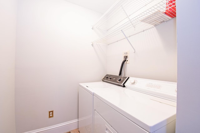 clothes washing area featuring laundry area, washing machine and clothes dryer, and baseboards