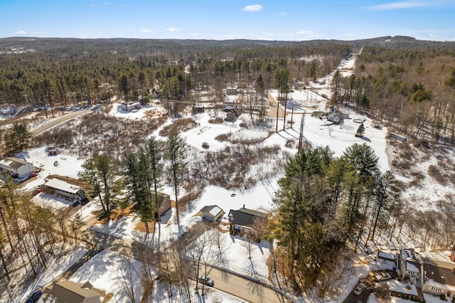 snowy aerial view featuring a wooded view