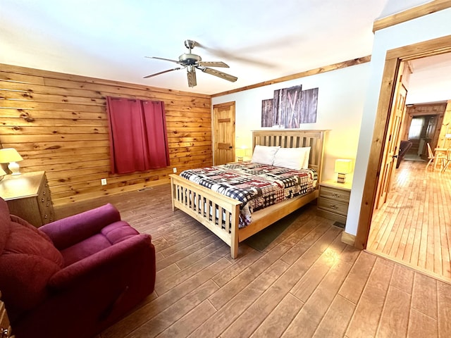 bedroom featuring ceiling fan, wood walls, wood finished floors, and crown molding