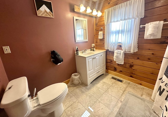 bathroom with toilet, vanity, visible vents, and wooden walls