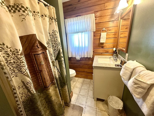 bathroom featuring vanity, toilet, and wooden walls