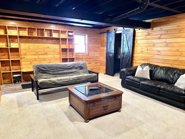 living area with carpet floors, a barn door, and wooden walls