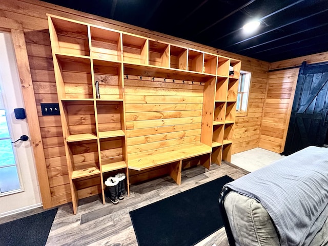 bedroom with wood finished floors, wooden walls, and a barn door