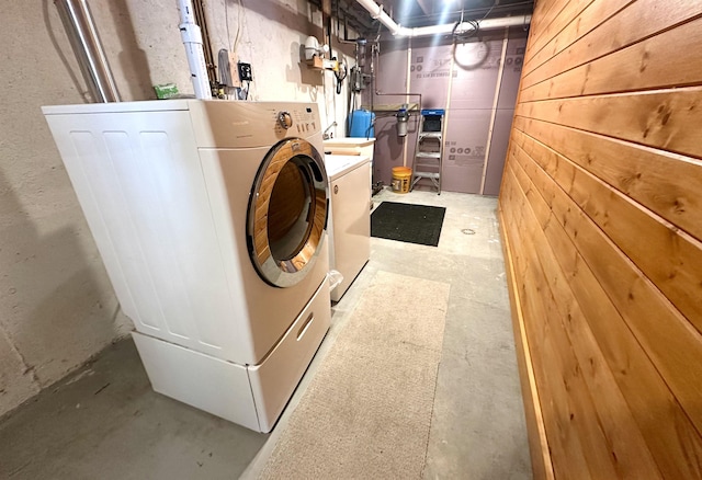 washroom featuring laundry area, washing machine and dryer, and wooden walls