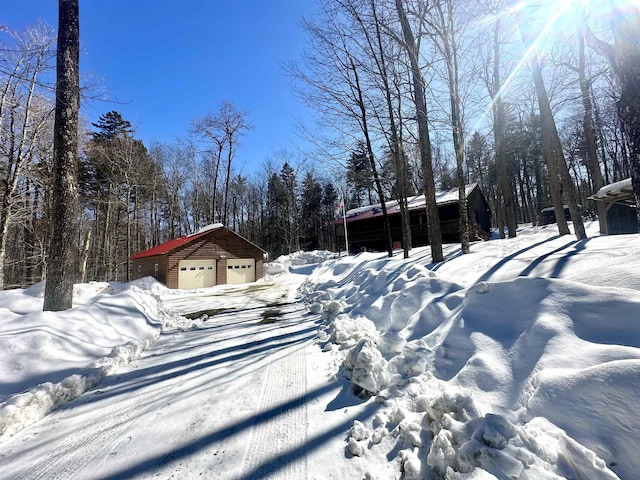 snowy yard featuring a garage and an outbuilding