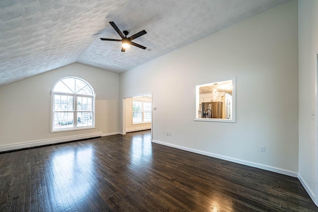 spare room featuring dark wood-style floors, vaulted ceiling, a textured ceiling, and baseboards