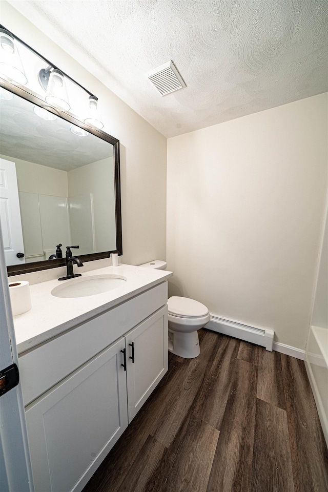 bathroom with visible vents, baseboard heating, a textured ceiling, vanity, and wood finished floors