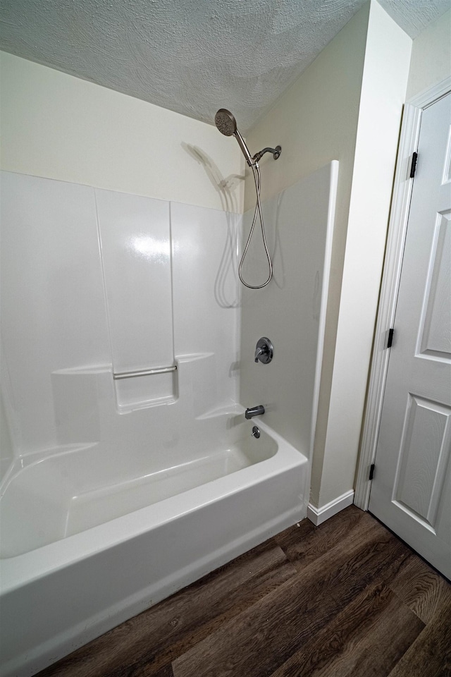 full bathroom with a textured ceiling, wood finished floors, and shower / bathing tub combination