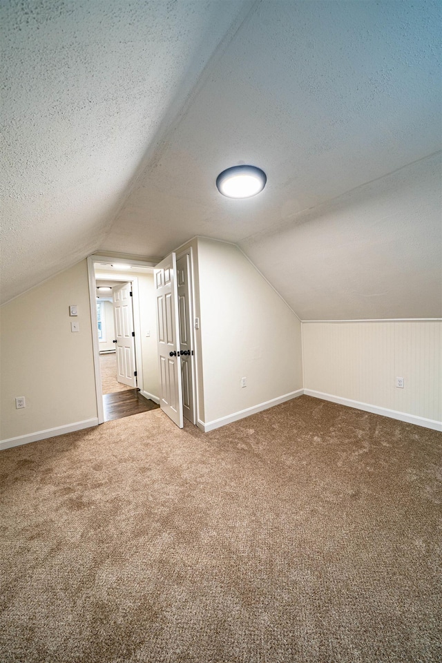 bonus room featuring lofted ceiling, baseboards, a textured ceiling, and carpet flooring